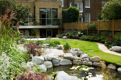 This is an example of a medium sized traditional back formal partial sun raised pond for summer in London with natural stone paving.