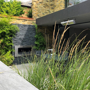 Geometrischer, Mittelgroßer, Halbschattiger Moderner Garten im Sommer, hinter dem Haus mit Kamin und Natursteinplatten in London