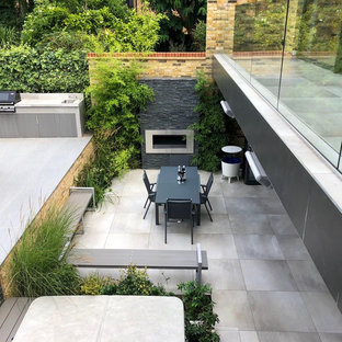 Geometrischer, Mittelgroßer, Halbschattiger Moderner Garten im Sommer, hinter dem Haus mit Kamin und Natursteinplatten in London