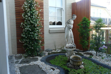 Ejemplo de jardín contemporáneo pequeño en patio lateral con fuente, exposición parcial al sol y gravilla