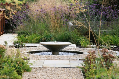 This is an example of a large contemporary back garden in Berkshire with a water feature and gravel.