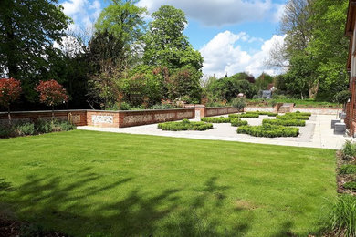 This is an example of a large contemporary back full sun garden for summer in Buckinghamshire with natural stone paving.