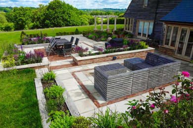 Design ideas for a large rural back full sun garden for summer in Sussex with natural stone paving.