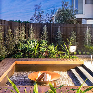 Cette photo montre un jardin arrière tendance de taille moyenne avec un foyer extérieur, une exposition ensoleillée et du gravier.