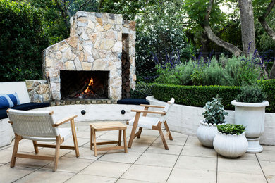 Foto di un piccolo patio o portico chic in cortile con un caminetto e pavimentazioni in pietra naturale