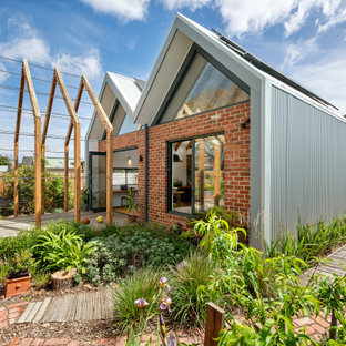 Inspiration for a contemporary backyard full sun garden in Melbourne with brick pavers and a wood fence.