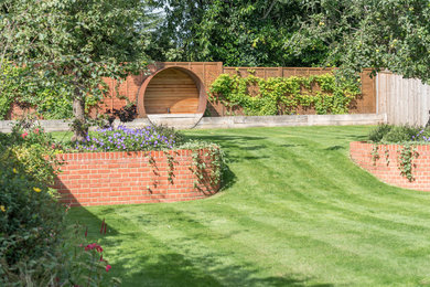 Medium sized contemporary back formal partial sun garden for summer in Berkshire with a retaining wall and brick paving.