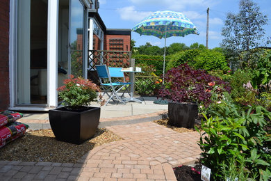 Стильный дизайн: маленький солнечный, летний участок и сад на заднем дворе в морском стиле с растениями в контейнерах, хорошей освещенностью и мощением тротуарной плиткой для на участке и в саду - последний тренд