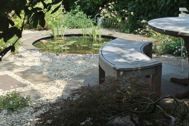 Inspiration for a medium sized contemporary back partial sun garden in Oxfordshire with a water feature and natural stone paving.