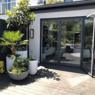 Geometrischer, Kleiner Moderner Garten im Sommer, hinter dem Haus mit Kamin, direkter Sonneneinstrahlung und Dielen in London