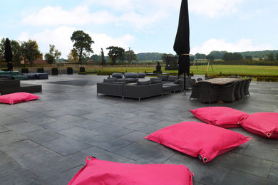 Imagen de jardín actual extra grande en patio trasero con exposición total al sol y adoquines de piedra natural