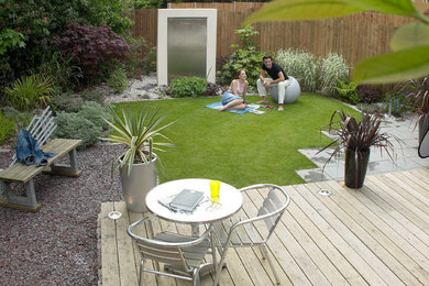 Ejemplo de jardín actual de tamaño medio en verano en patio trasero con jardín francés, muro de contención, exposición total al sol y adoquines de ladrillo