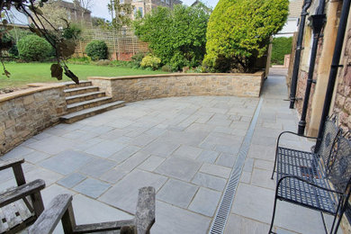 Design ideas for a medium sized classic back formal full sun garden for summer in Other with a retaining wall and natural stone paving.