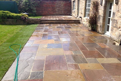 Large classic back garden in Other with a garden path and natural stone paving.