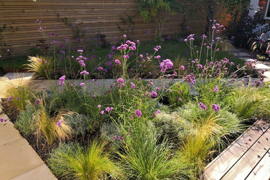 This is an example of a traditional front partial sun garden in Sussex with a garden path and natural stone paving.