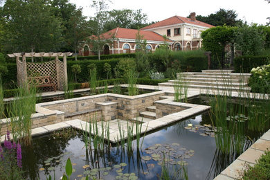 Large traditional back formal garden for summer in Berkshire with a water feature and natural stone paving.