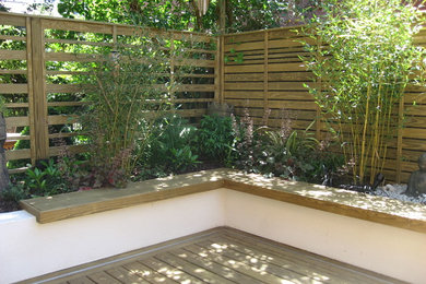 Diseño de jardín actual pequeño en verano en patio con muro de contención, exposición parcial al sol y entablado
