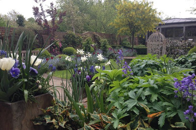 Cette image montre un jardin à la française arrière traditionnel de taille moyenne et au printemps avec une exposition partiellement ombragée.