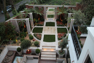 Medium sized contemporary back formal garden in London with natural stone paving and a water feature.