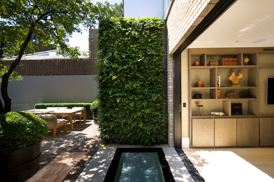 Inspiration for a large contemporary courtyard partial sun garden for spring in London with a living wall and brick paving.