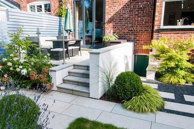 Imagen de jardín clásico renovado pequeño en verano en patio trasero con jardín francés, exposición total al sol y adoquines de piedra natural