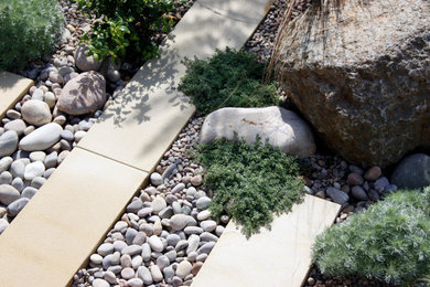 Foto de jardín actual pequeño en verano en patio trasero con jardín francés, exposición total al sol y adoquines de piedra natural