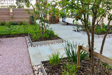 На фото: солнечный регулярный сад на переднем дворе в современном стиле с садовой дорожкой или калиткой, хорошей освещенностью и покрытием из каменной брусчатки