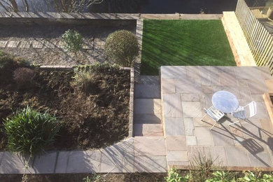 Large contemporary sloped garden in Other with natural stone paving.