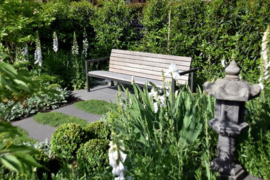 Imagen de jardín tradicional de tamaño medio en primavera en patio delantero con exposición total al sol y adoquines de piedra natural