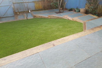 This is an example of a medium sized back garden in Sussex with concrete paving.