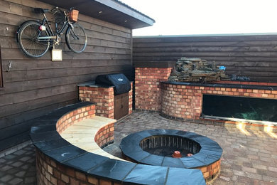 Inspiration for a small rustic courtyard formal partial sun garden for summer in West Midlands with a fire feature and brick paving.