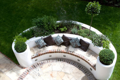 This is an example of a large contemporary backyard stone formal garden in London.