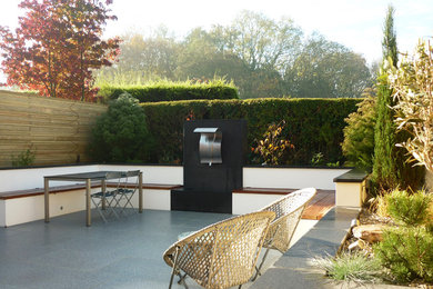 Foto de jardín contemporáneo pequeño en patio trasero con jardín francés, fuente, exposición parcial al sol y adoquines de piedra natural