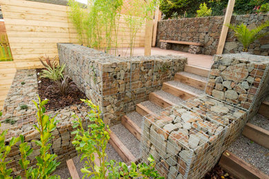 This is an example of a medium sized contemporary back fully shaded garden for spring in Other with a retaining wall and gravel.