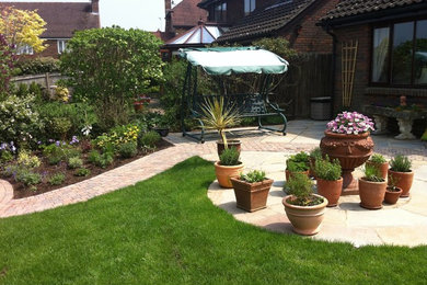 Kleiner Klassischer Garten im Sommer, hinter dem Haus mit direkter Sonneneinstrahlung und Betonboden in Gloucestershire