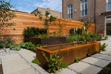 Imagen de jardín contemporáneo de tamaño medio en patio trasero con exposición total al sol y adoquines de hormigón