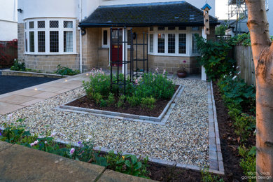 Inspiration for a small traditional front partial sun garden with a flowerbed, natural stone paving and a wood fence.