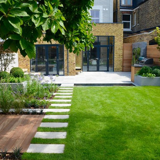 Mittelgroßer Moderner Garten im Sommer, hinter dem Haus mit Teich, direkter Sonneneinstrahlung und Natursteinplatten in London