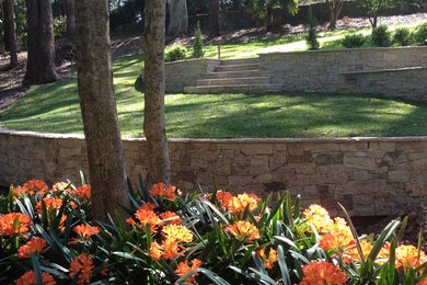 Exemple d'un jardin arrière avec un mur de soutènement, une exposition partiellement ombragée et des pavés en pierre naturelle.