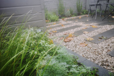 This is an example of a small modern back partial sun garden in London with a flowerbed and natural stone paving.