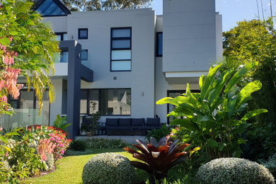 Idee per un giardino tropicale esposto in pieno sole dietro casa con pavimentazioni in pietra naturale