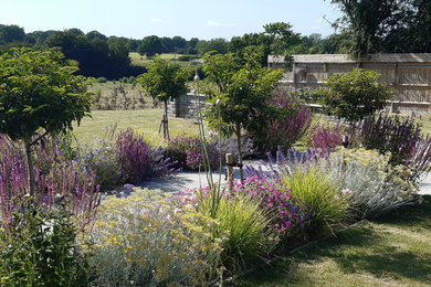 Photo of a large farmhouse back formal full sun garden for summer in Sussex with a garden path and natural stone paving.