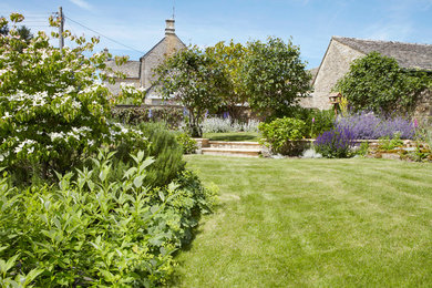 Ejemplo de jardín campestre grande en patio trasero con jardín francés