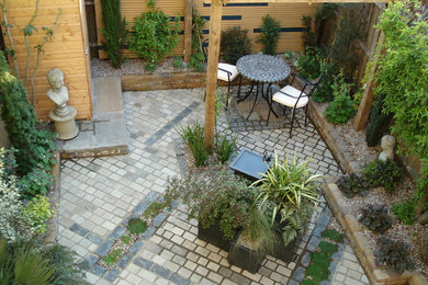 This is an example of a small bohemian back partial sun garden for summer in Kent with an outdoor sport court and natural stone paving.