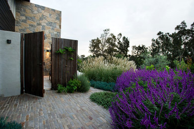 Aménagement d'un grand jardin sur cour avec une exposition ensoleillée et des pavés en pierre naturelle.