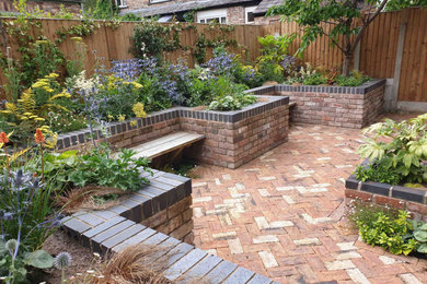 Small contemporary back xeriscape partial sun garden in Manchester with brick paving.