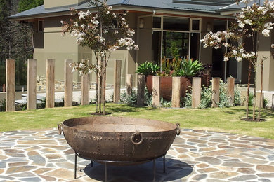 Diseño de jardín actual grande en patio trasero con jardín francés, brasero, exposición total al sol y adoquines de piedra natural