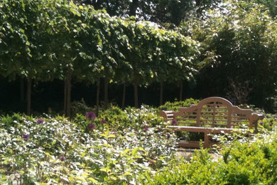 Modelo de jardín tradicional grande en verano en patio trasero con jardín francés, exposición parcial al sol y adoquines de ladrillo