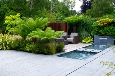 Design ideas for a medium sized contemporary back full sun garden for summer in London with a water feature and natural stone paving.