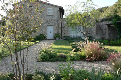 Large farmhouse side formal garden in Other with gravel.